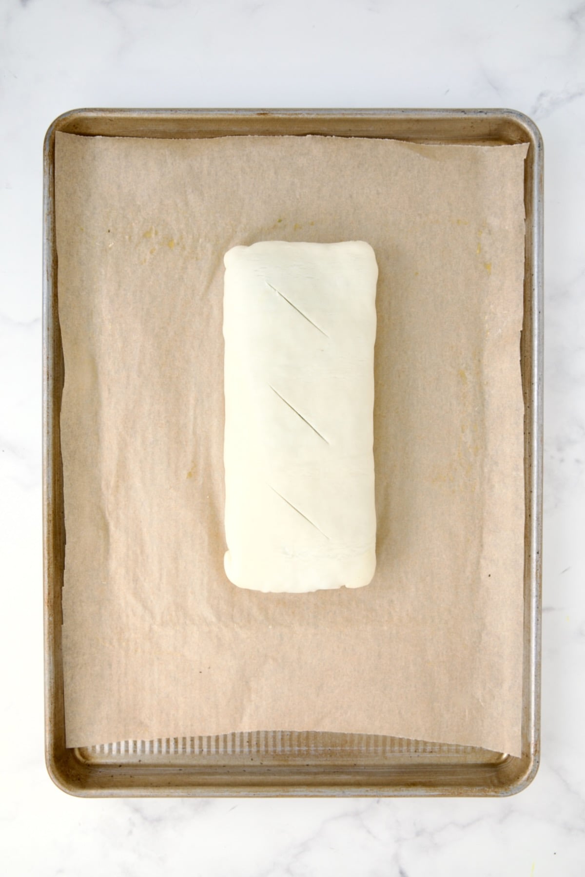 Fully assembled Italian Vegetable Strudel turned over for baking with three slits cut in the top.
