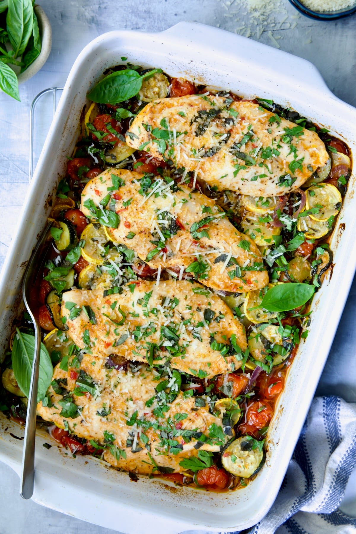 One-Pan Summer Vegetable and Chicken Bake in white rectangular baking dish.