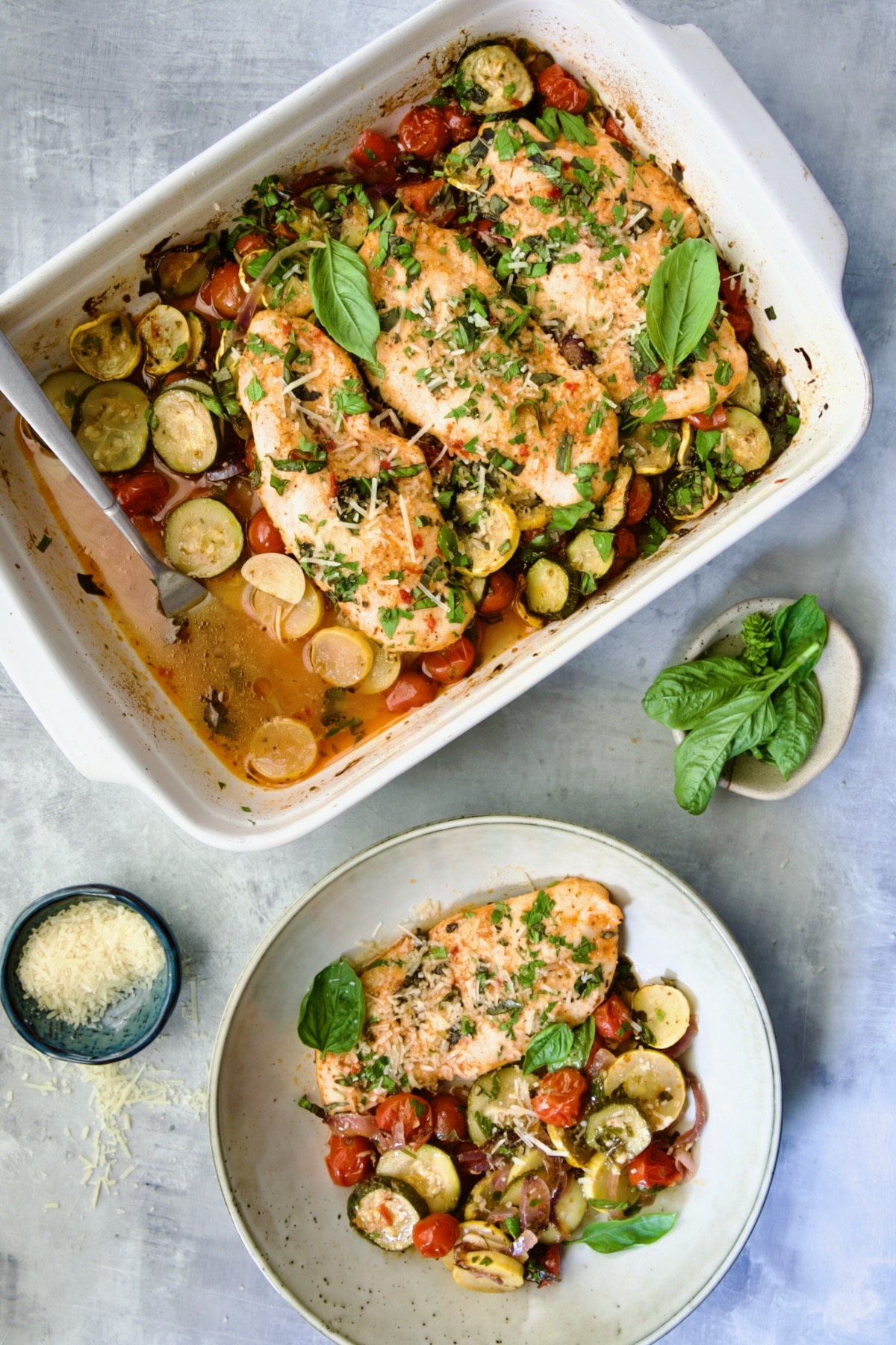 One-Pan Summer Vegetable and Chicken Bake in white rectangular baking dish with one serving removed to a plate.
