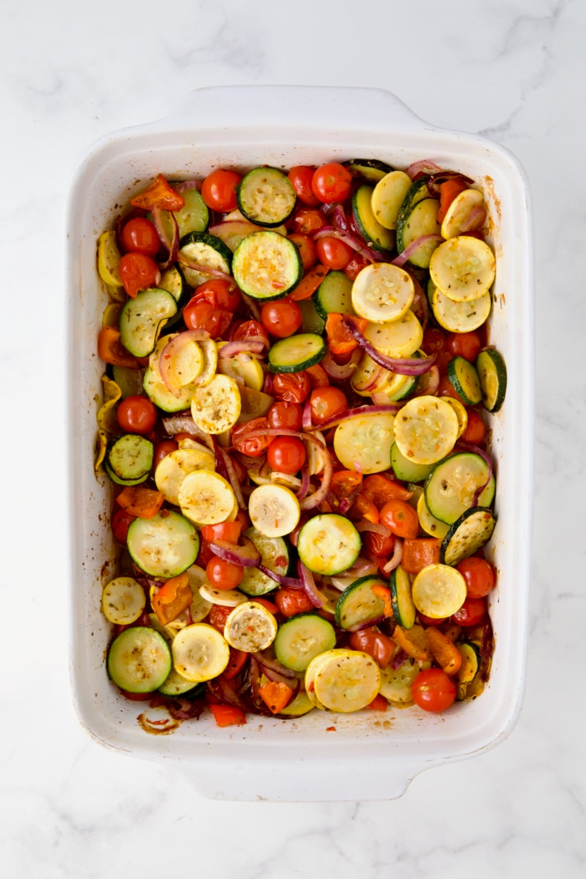 Semi-cooked vegetables in white rectangular baking dish.