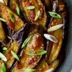Thai Sweet Chili Eggplant on blue oval plate garnished with scallions.