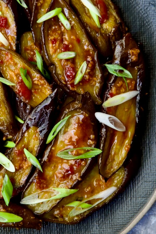 Thai Sweet Chili Eggplant on blue oval plate garnished with scallions.