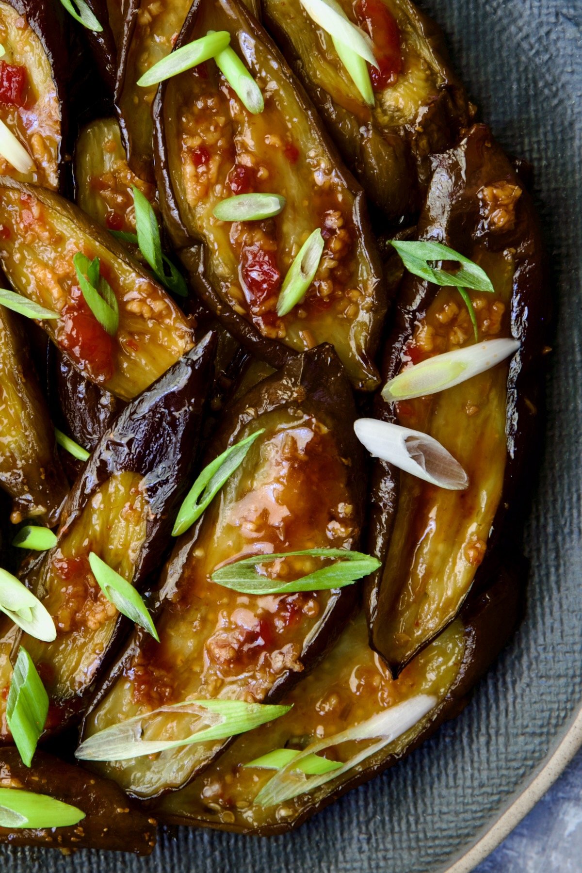 Thai Sweet Chili Eggplant on blue oval plate garnished with scallions.