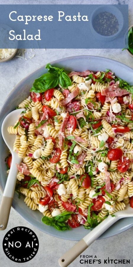 Pinterest graphic for Caprese Pasta Salad showing it in a blue bowl with white serving utensils.
