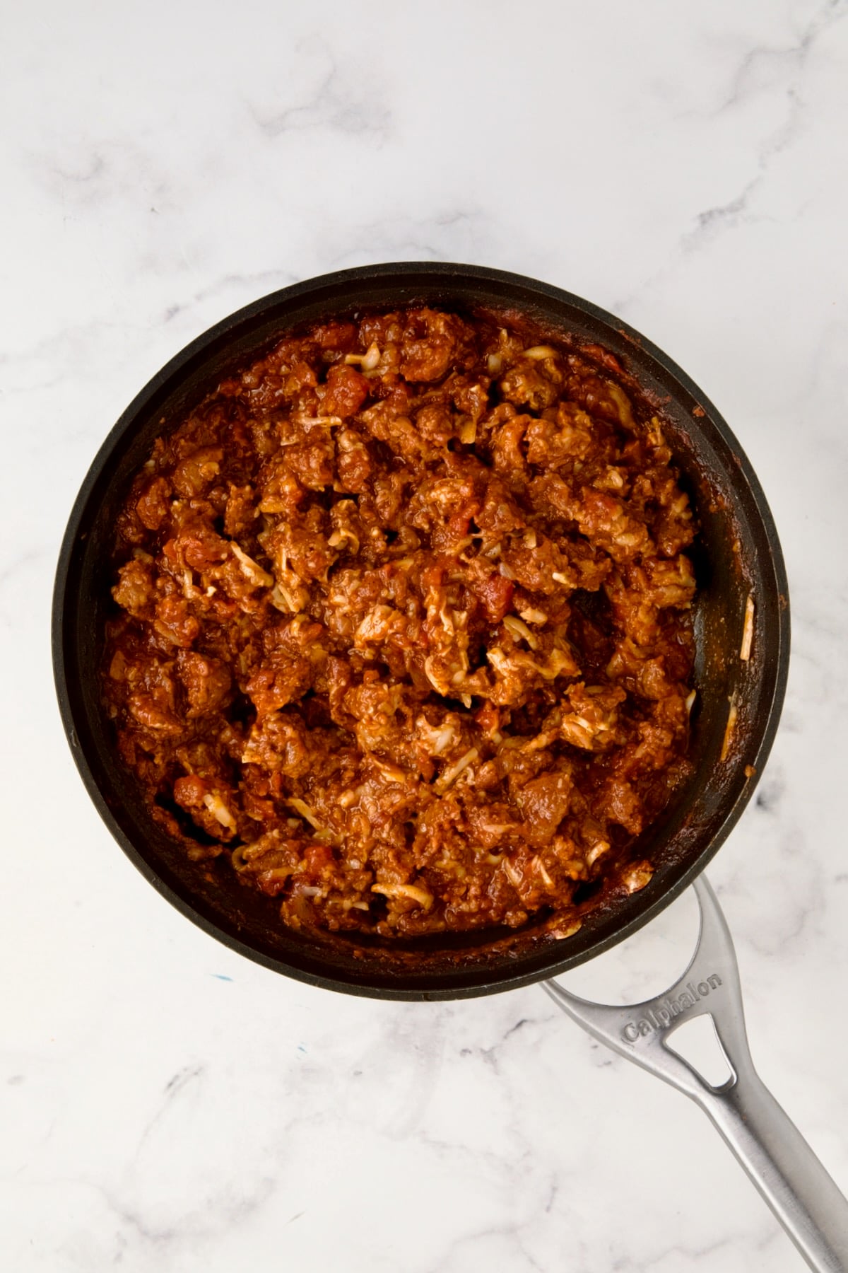 Cooked chorizo filling in nonstick skillet with half the cheese added.