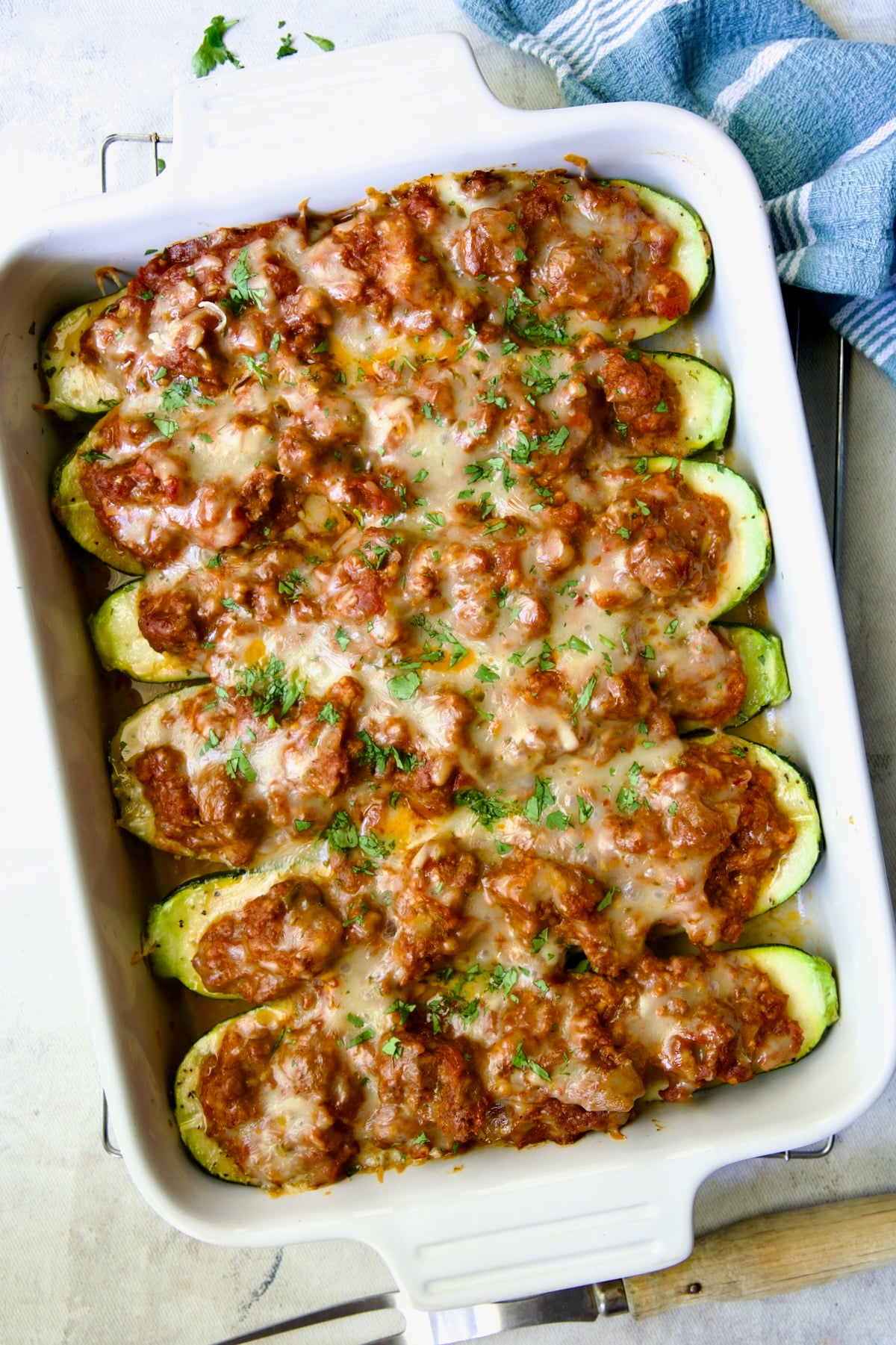 Six baked Chorizo-Stuffed Zucchini in white rectangular baking dish.