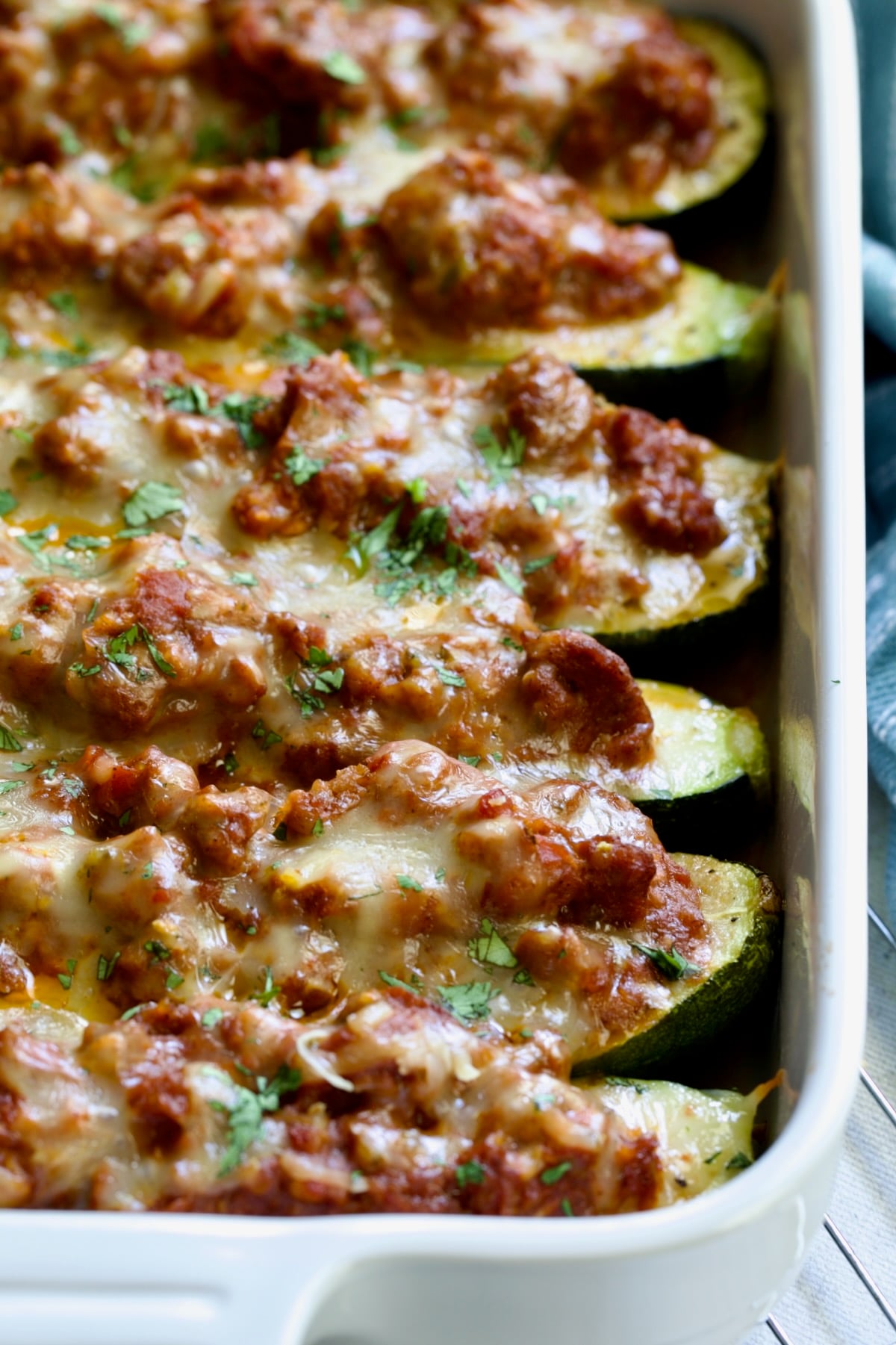 Six baked Chorizo-Stuffed Zucchini in white rectangular baking dish.