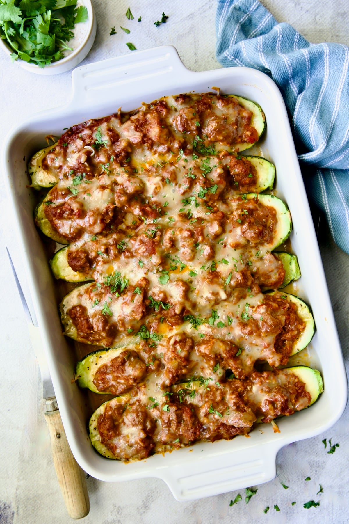 Six baked Chorizo-Stuffed Zucchini in white rectangular baking dish.