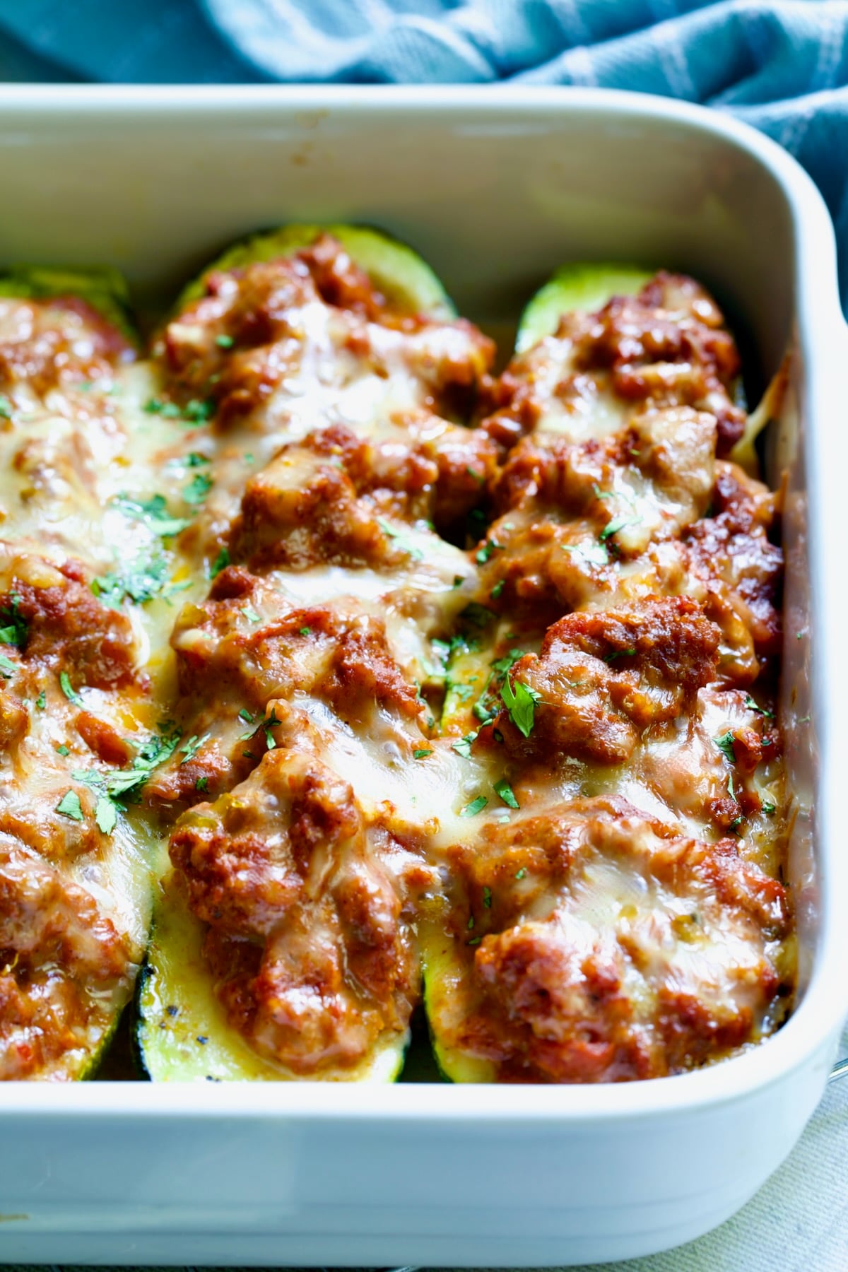 Close-up of two Chorizo-Stuffed Zucchini in white rectangular baking dish.