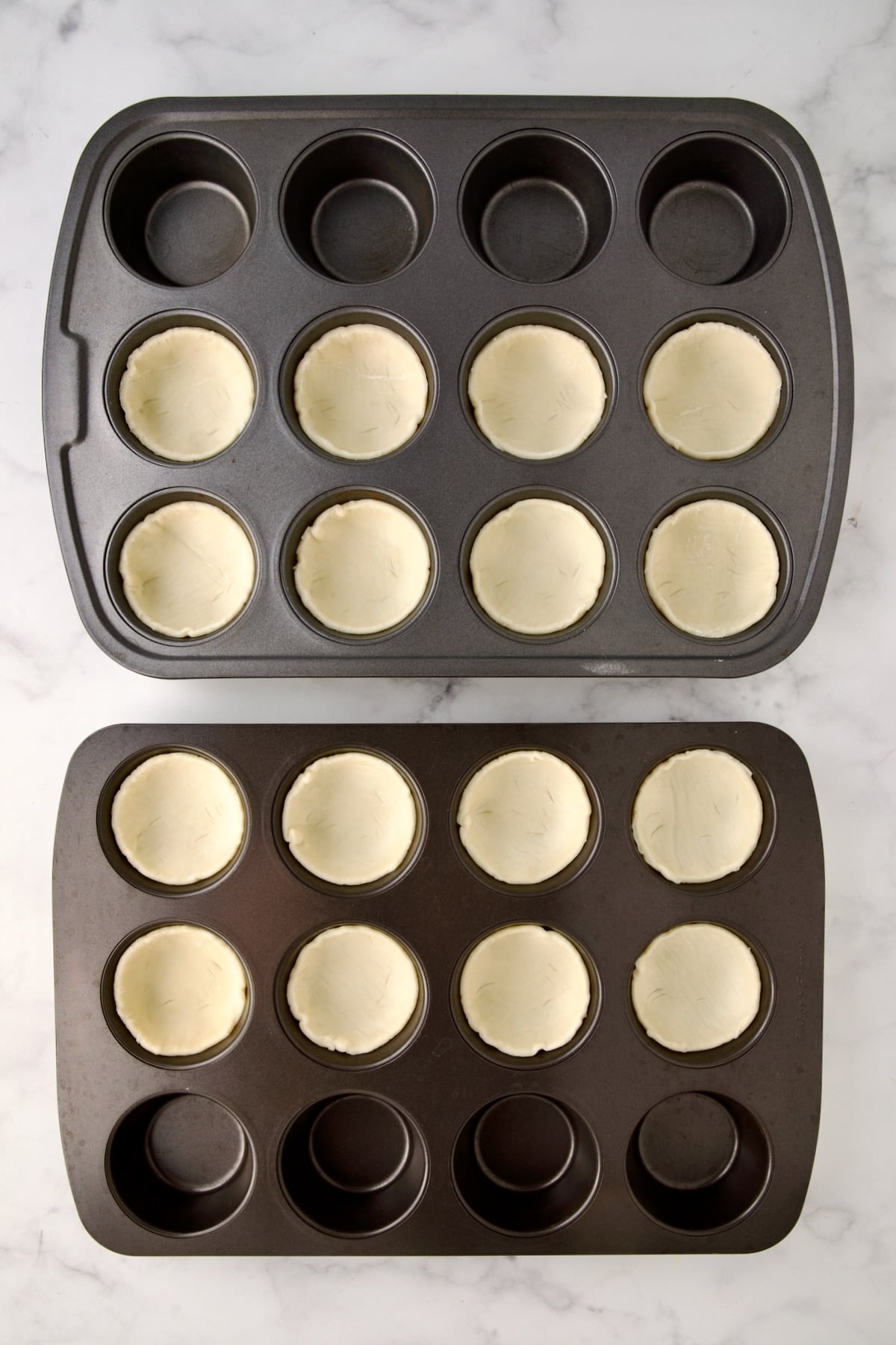Puff pastry rounds in two 12-cup muffin pans.