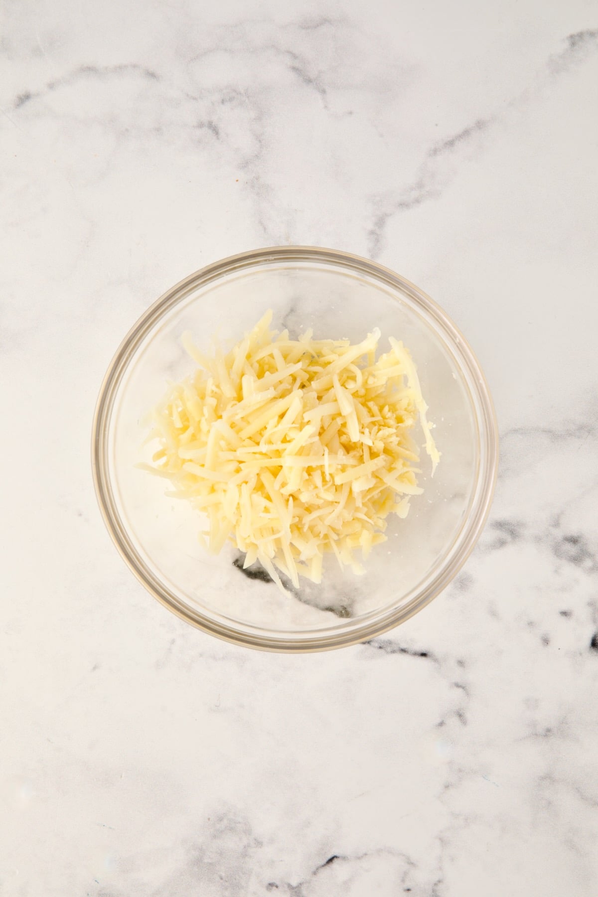 Grated cheese in glass bowl.