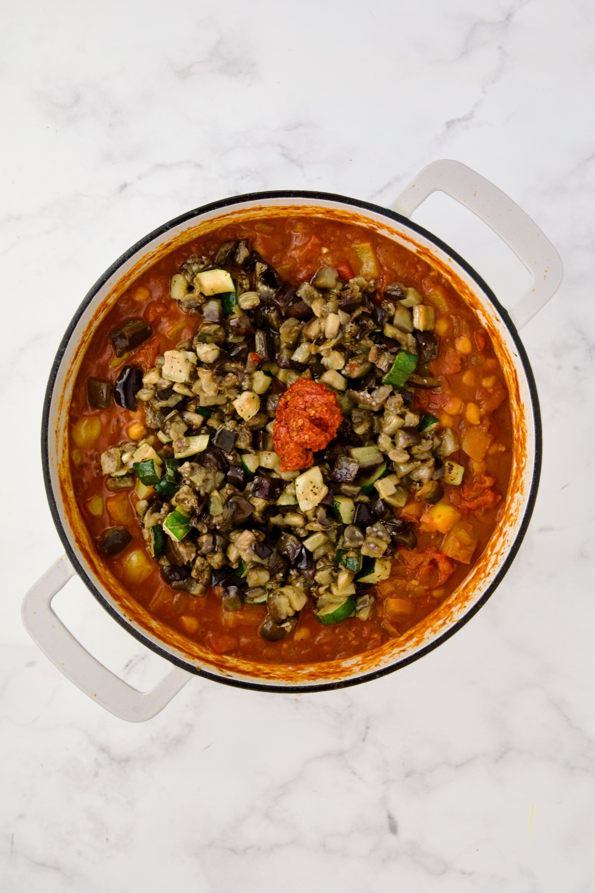 Zucchini, eggplant and harissa added to stew.