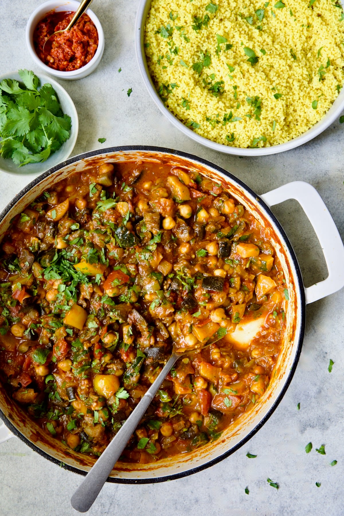Finished Moroccan Eggplant Stew in white enamel cast iron skillet with bowl of couscous.