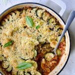 Summer Vegetable Cassoulet in white enamel cast iron skillet with serving spoon scooping some up.